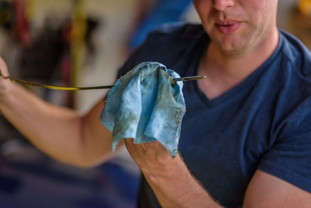 ¿El lavado de la transmisión dañará mi vehículo? 7 Hombre comprobando el nivel de aceite en la varilla medidora